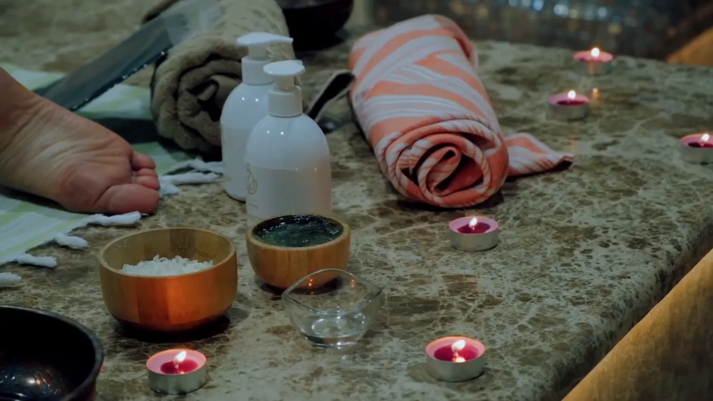 A spa ritual: candles, salt, oils and a towel on marble